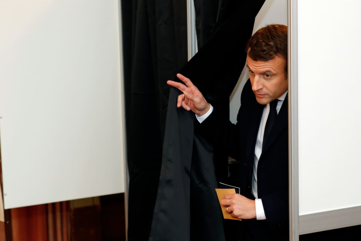 Macron tulee verhon takaa äänestyskopista.