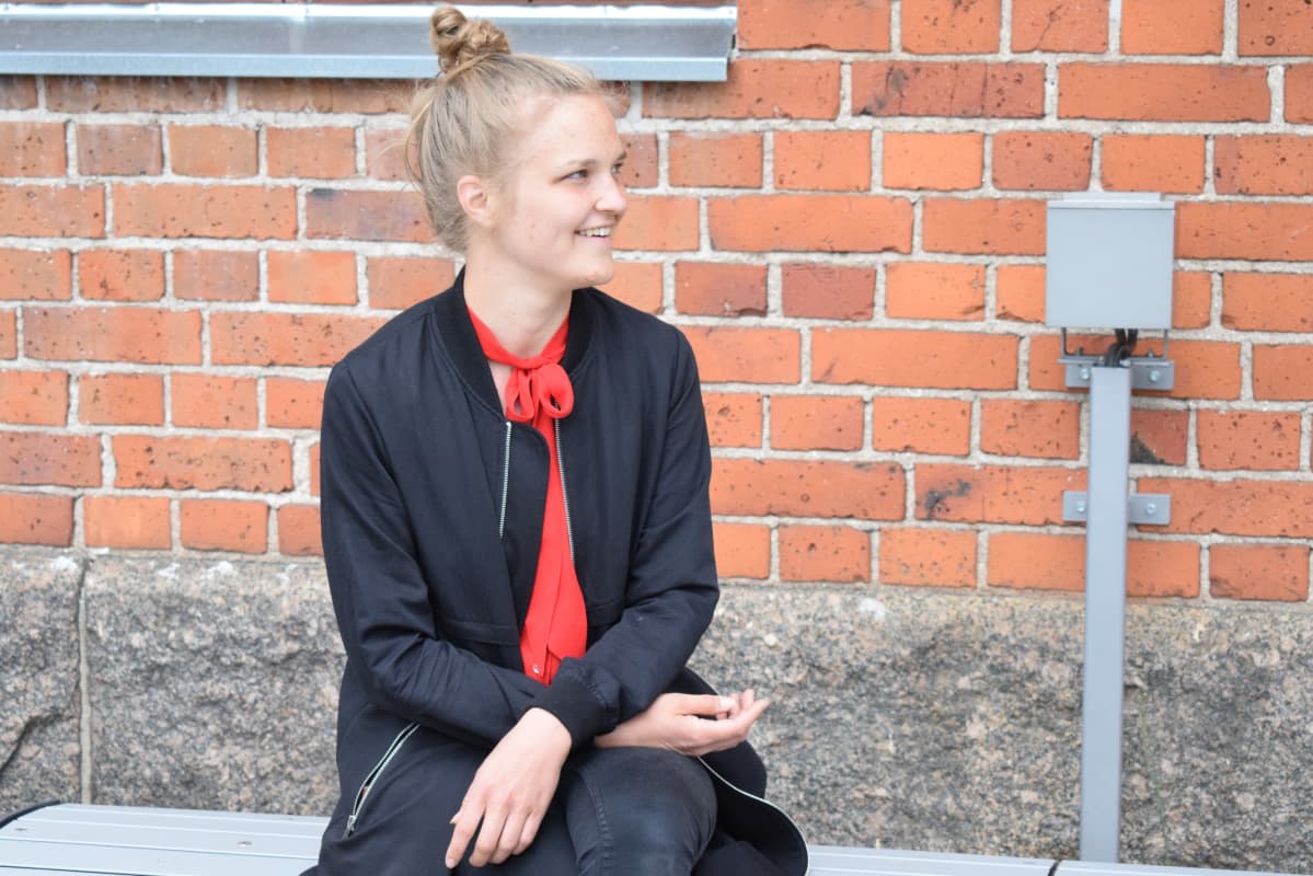 nainen istuu penkillä rakennuksen edessä
