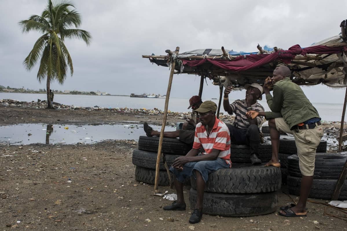 Neljä miestä istuu meren rannassa Cap Haitianissa Haitissa.