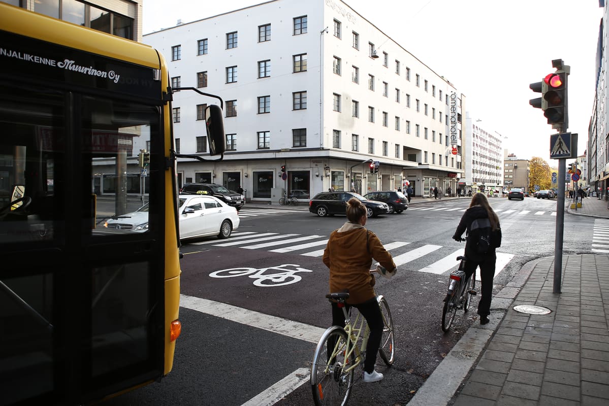 Polkupyöräilijät odottavat pyöräkaistalla, että liikennevalo muuttuu punaisesta vihreäksi.