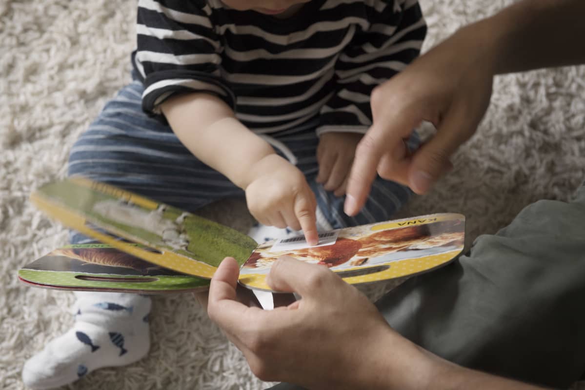 Lapsi katselee kuvakirjaa vanhempansa kanssa.