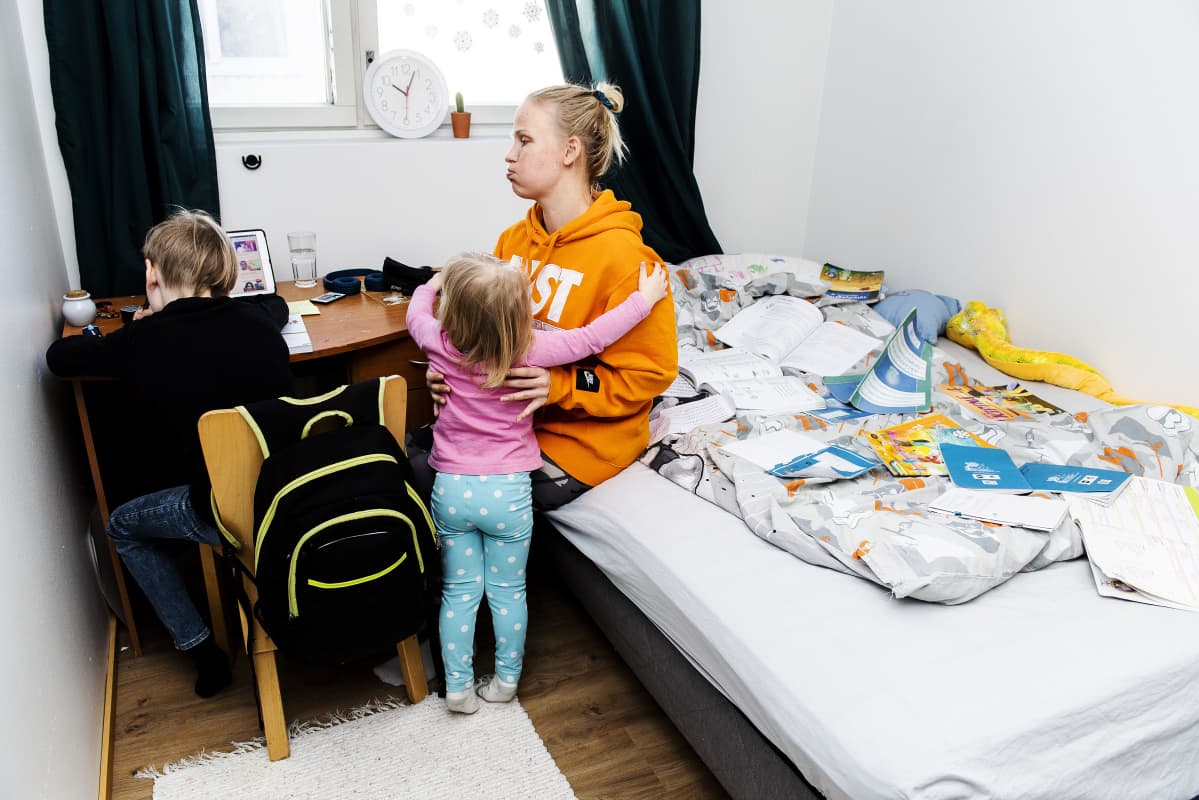 Leevi tekee tehtäviä, Miira nostaa Sofian syliin.