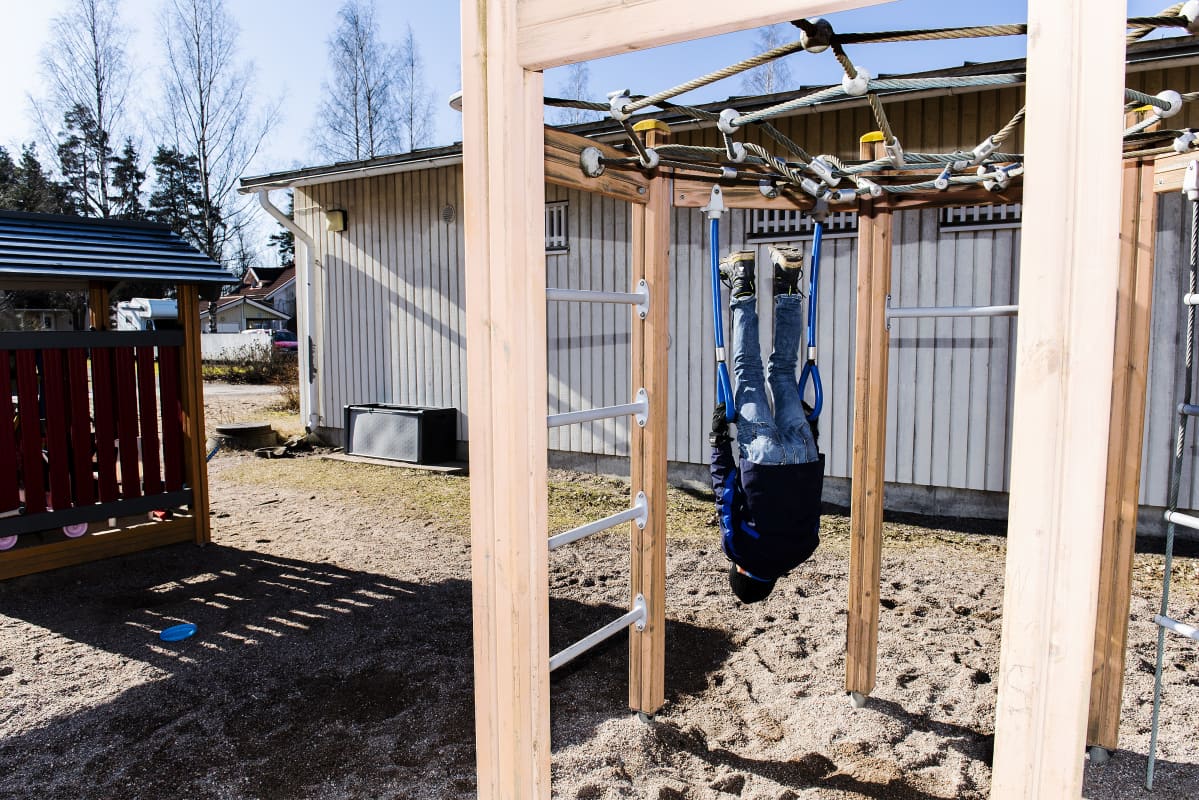 Leevi roikkuu leikkitelineessä pää alaspäin.