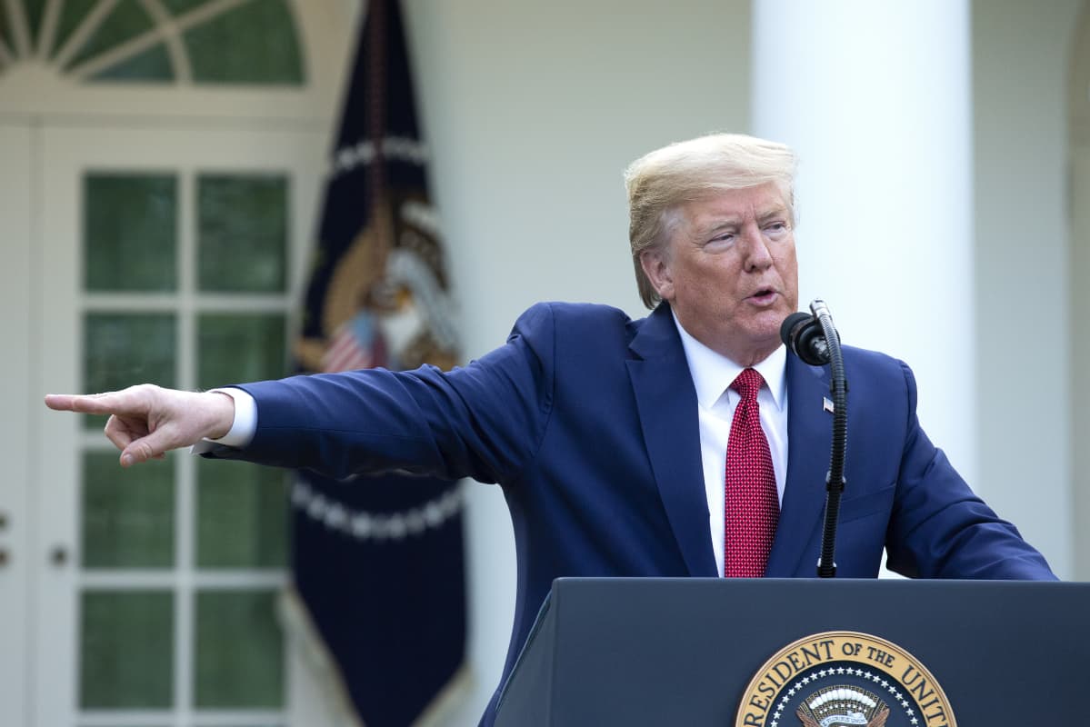 Donald Trump puhuu Valkoisen talon edessä ja osoittaa sormella oikealle puolelleen