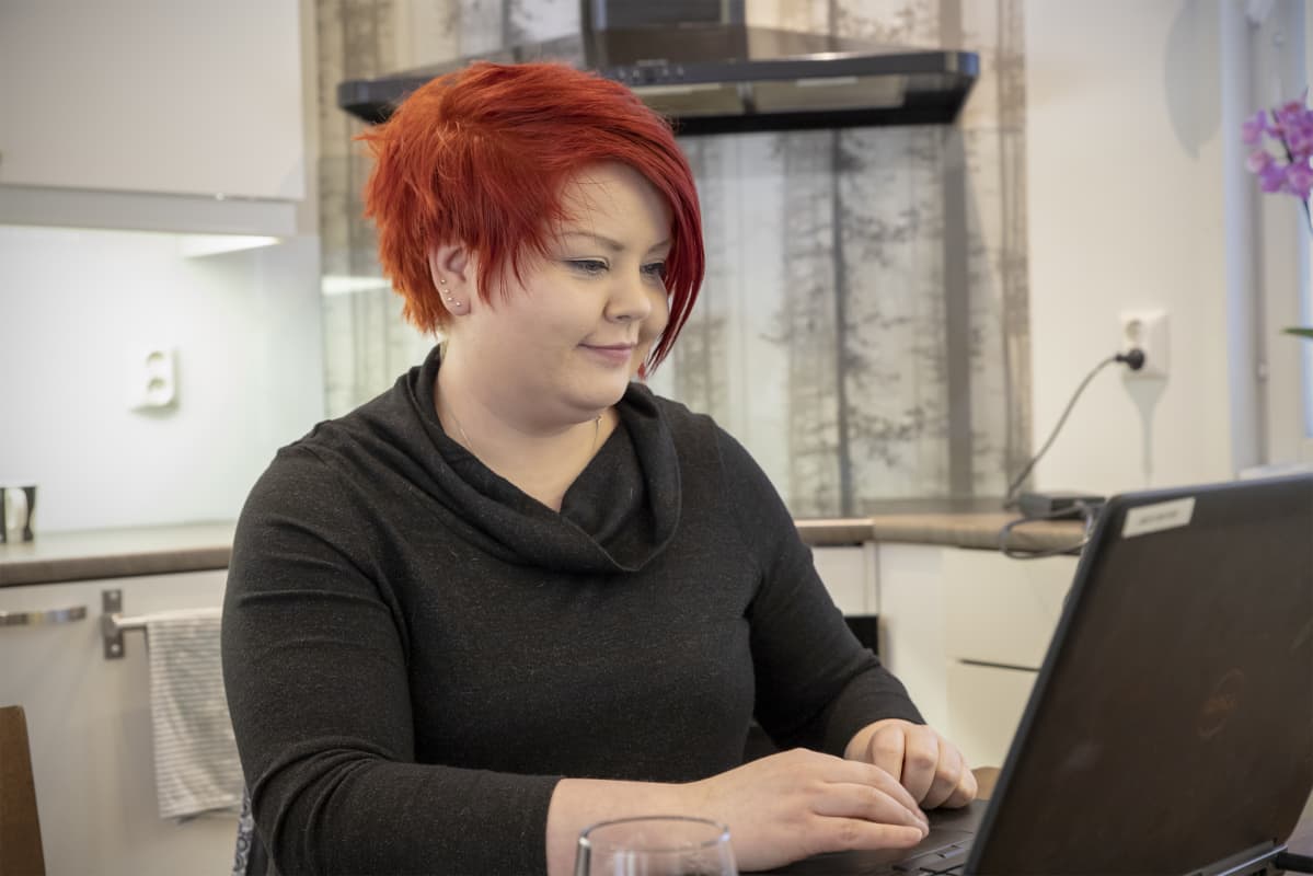Riikka Kohtamäki tekee töitä läppärillä keittiön pöydän ääressä