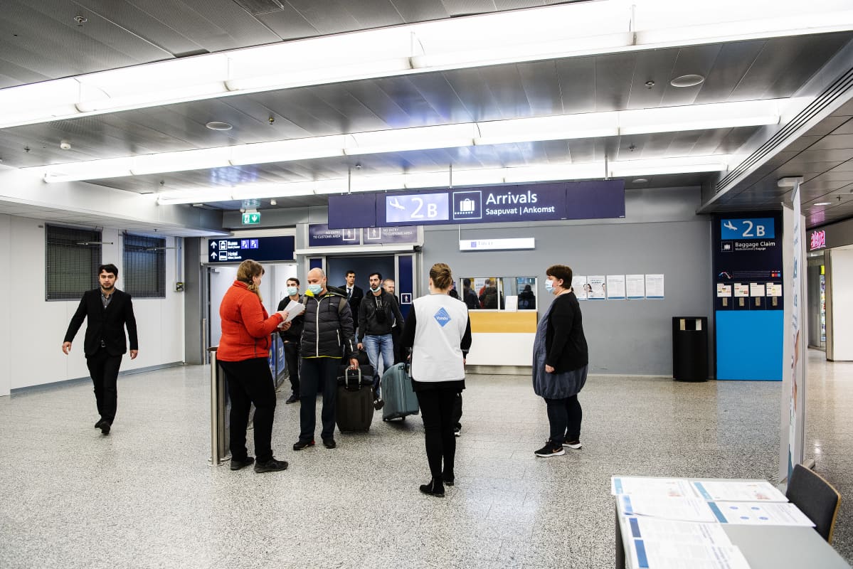 Kuvassa kausityöläisiä ohjeistetaan lentoasemalla karanteenisäännöistä.