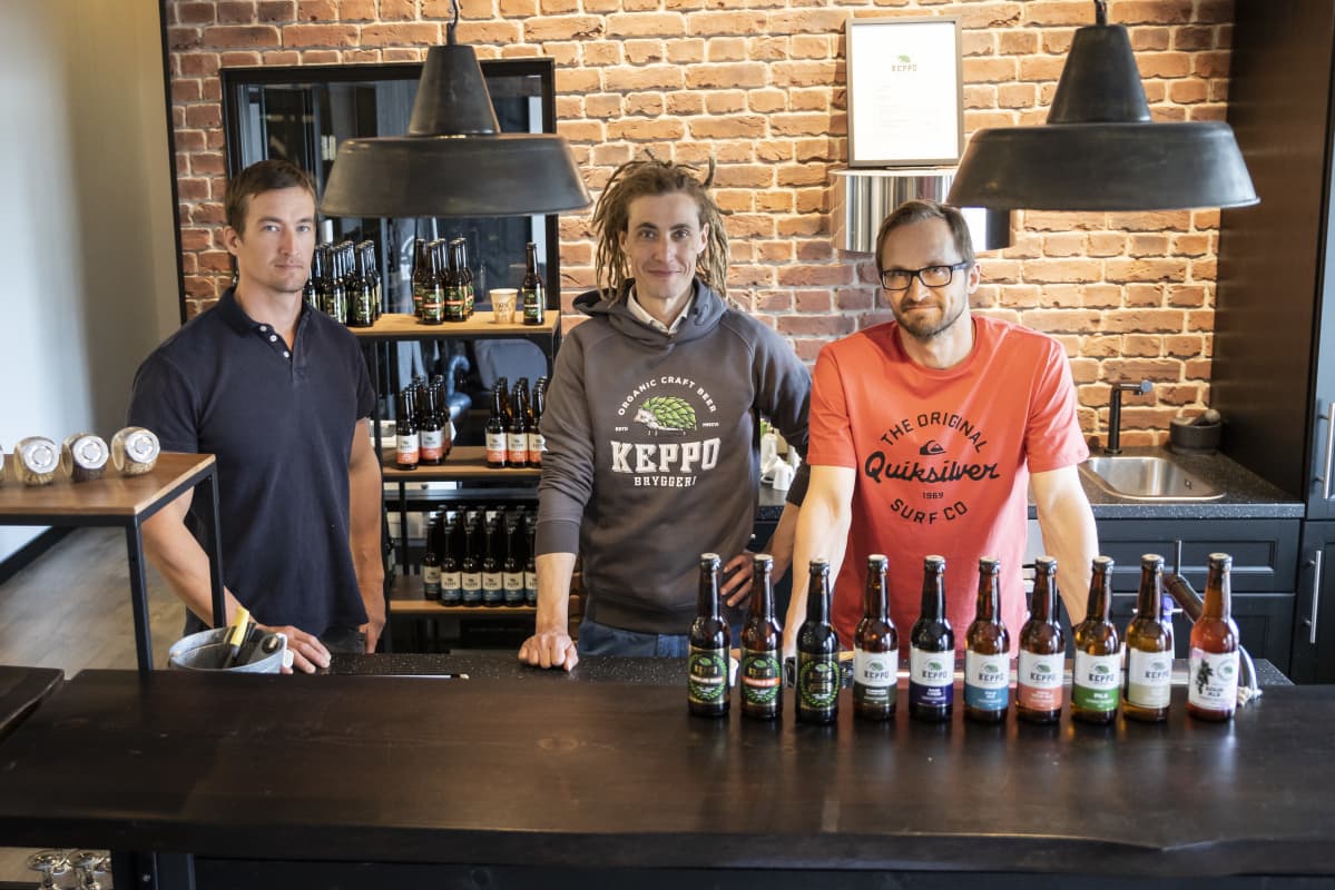 Kolme miestä nojailee tiskiin Keppo Bryggerin panimon myymälässä.