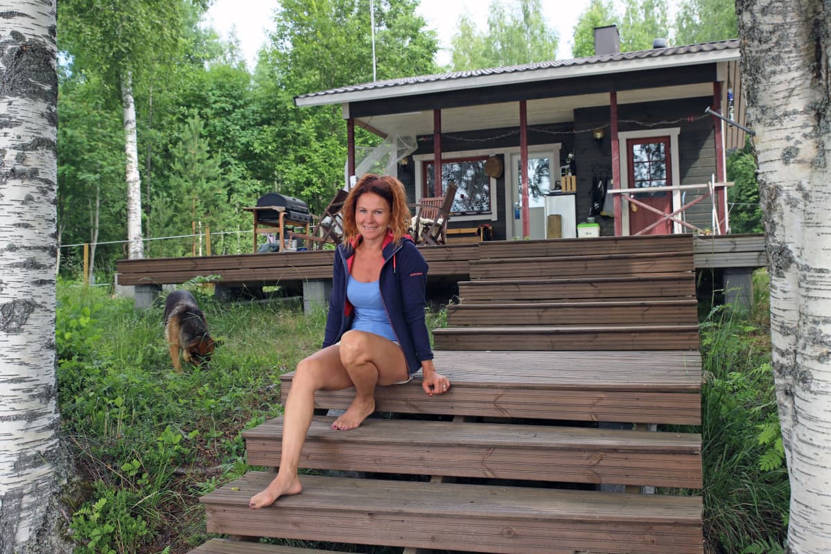 Melina Holmberg istuu mökkinsä kuistilla.