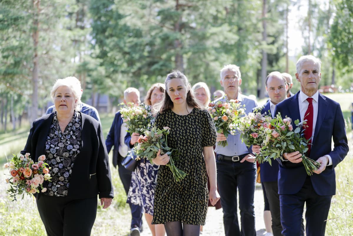 Erna Solberg ja muista muistojuhlaan osallistuneita kukkakimput kädessään.
