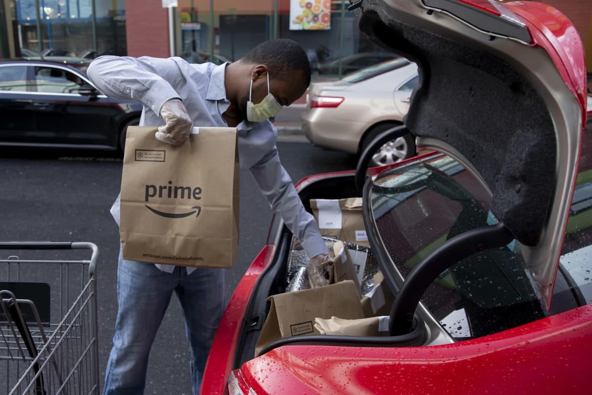 Amazonin kuljettaja lastaa ruokatoimituksia autoon Silver Springsissä, Marylandissä, 7.4.2020.