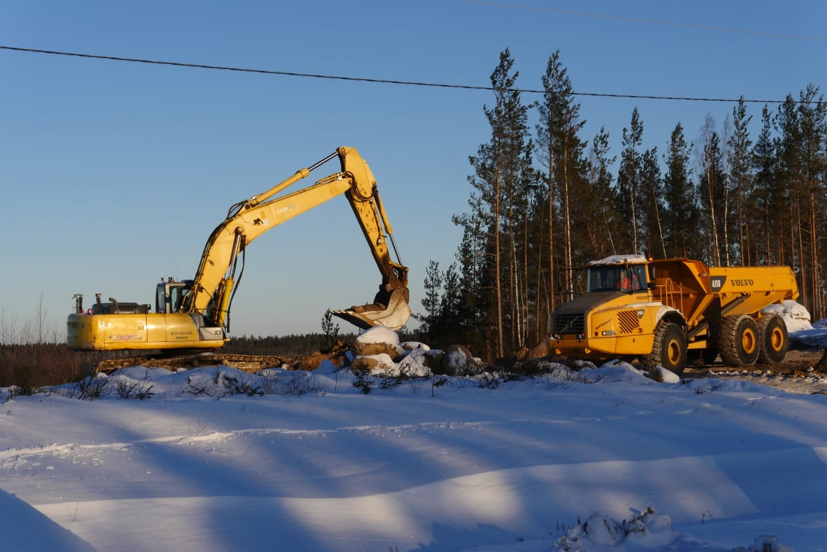 Kaksi työmaakonetta – kaivuri ja jumpperi – talvimaisemassa KymiRingin moottoriratatyömaalla.