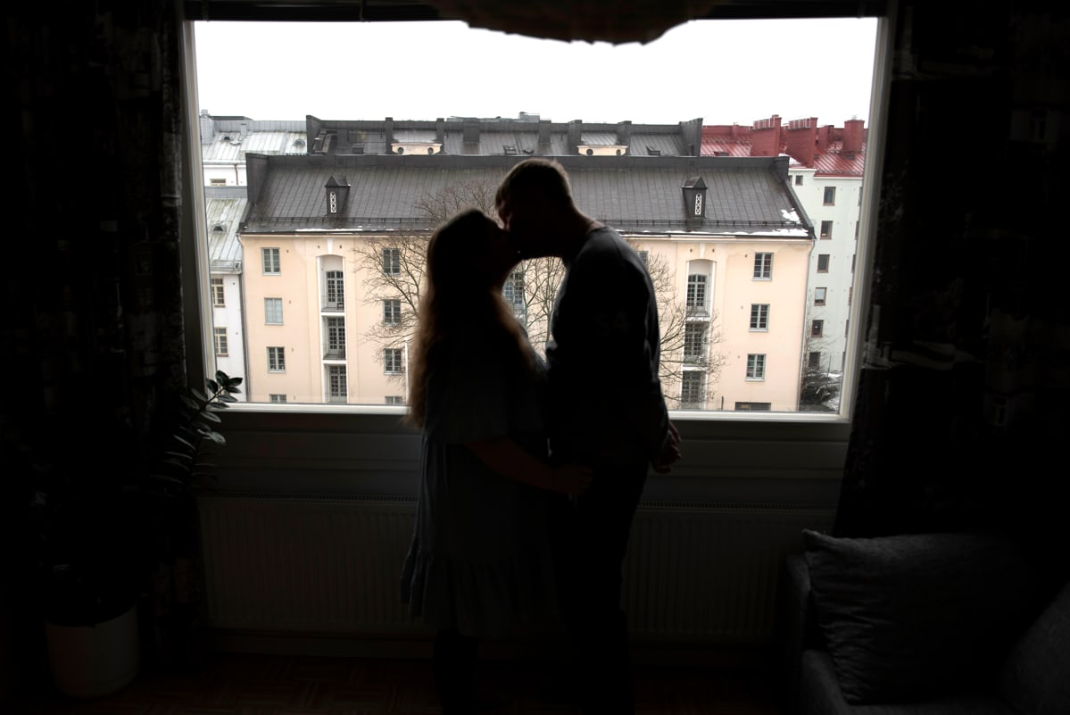 Pariskunta suutelee ikkunan edessä.