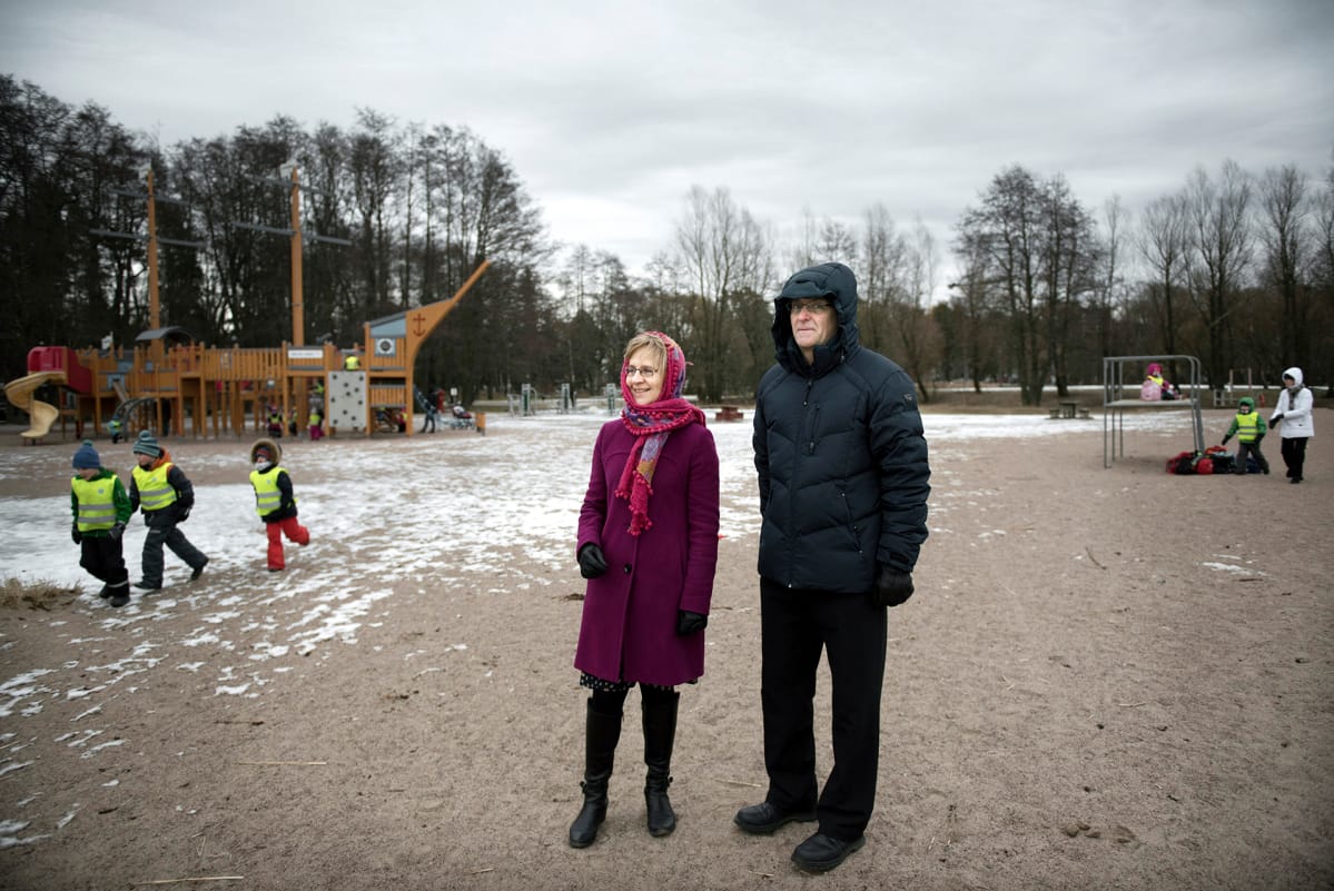 Pariskunta seisoo leikkipuiston edustalla.