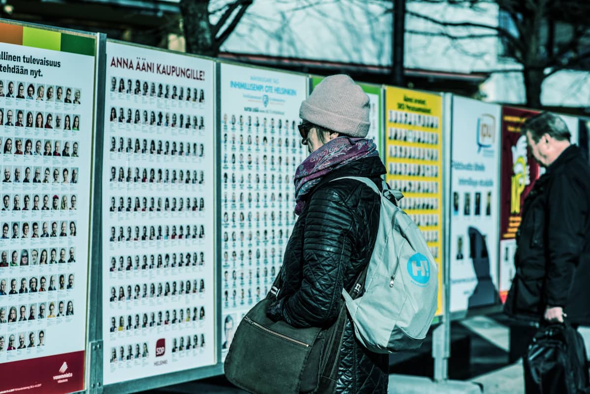 Äänestäjä puoluemainosten edessä.