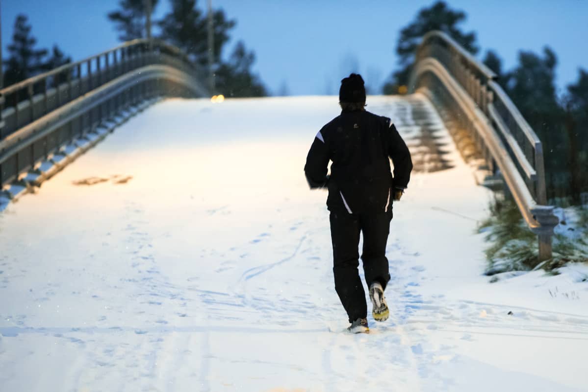 Lenkkeilijä lumisella lenkkipolulla.