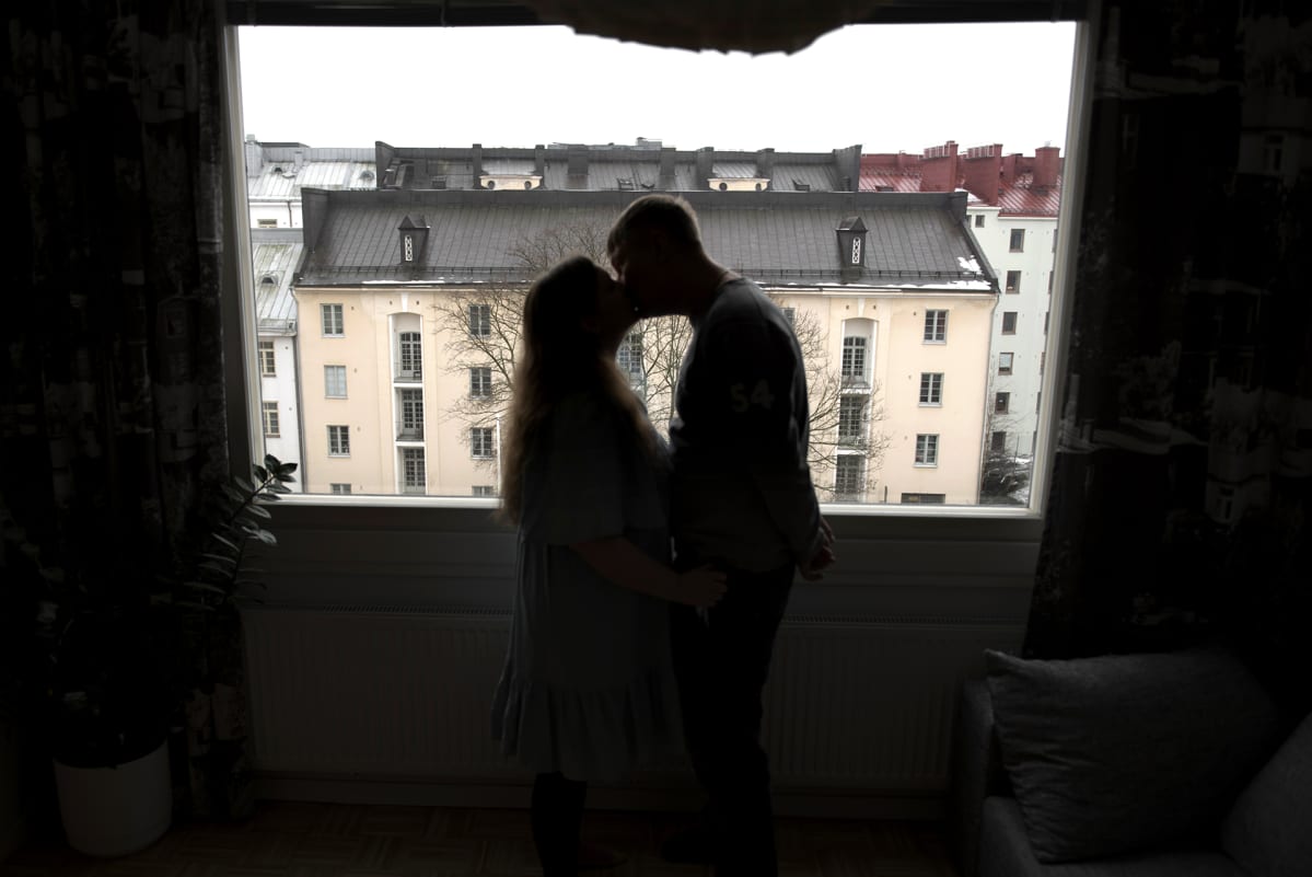 Pariskunta suutelee ikkunan edessä.