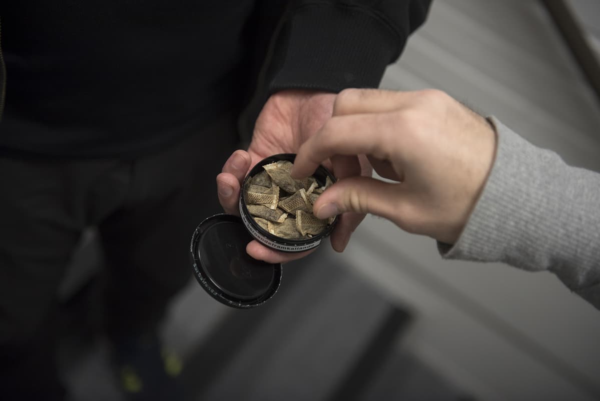 Mies ottaa toisen miehen tarjoamasta nuuskarasiasta nuuskapussia.