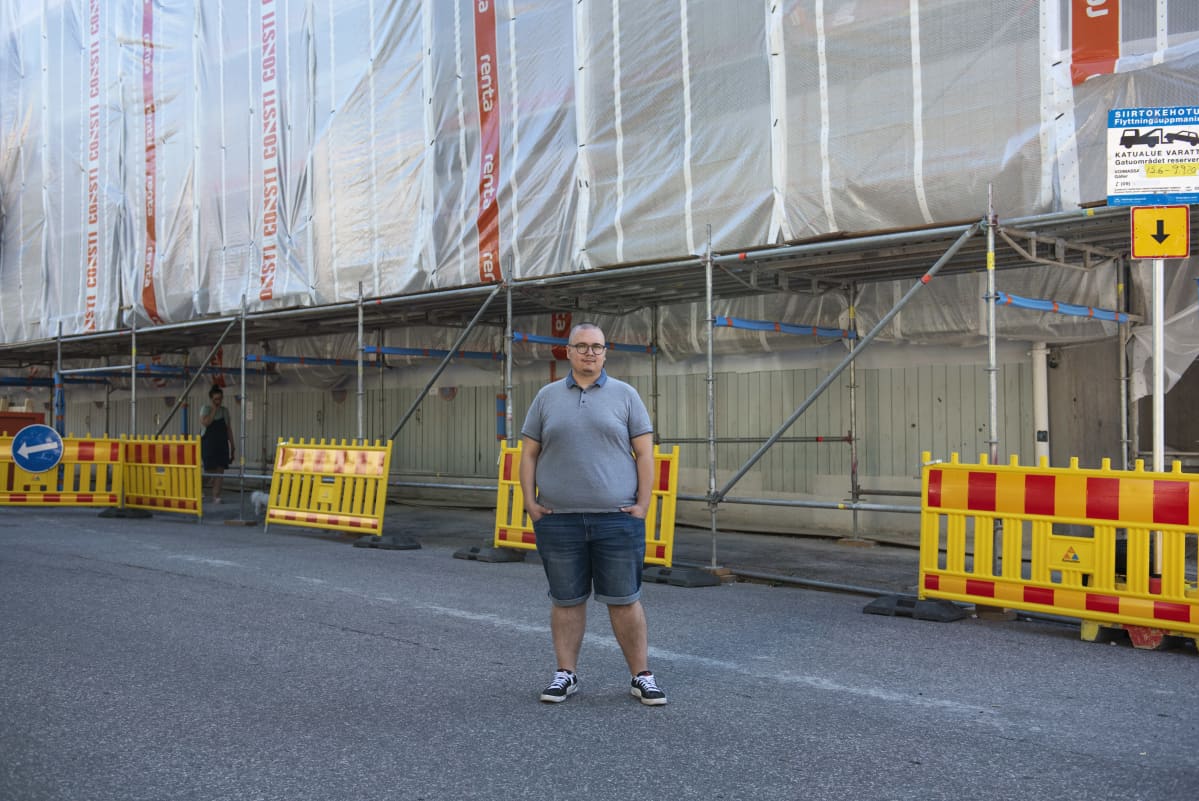 Benjamin Molini huputetun kotinsa edessä Haagassa. Talossa on käynnissä iso julkisivuremontti. enjamin Molini kotonaan Haagassa tietokoneen ääressä. Asunnon ikkunoista ei näy ulos eikä niitä saa auki, sillä talossa on käynnissä suuri julkisivuremontti.