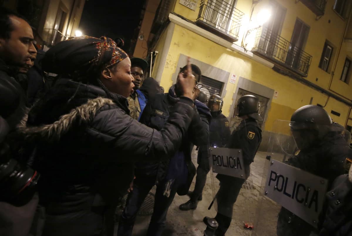 Afrikkalaisia maahanmuuttajia ja poliiseja Madridin kadulla.