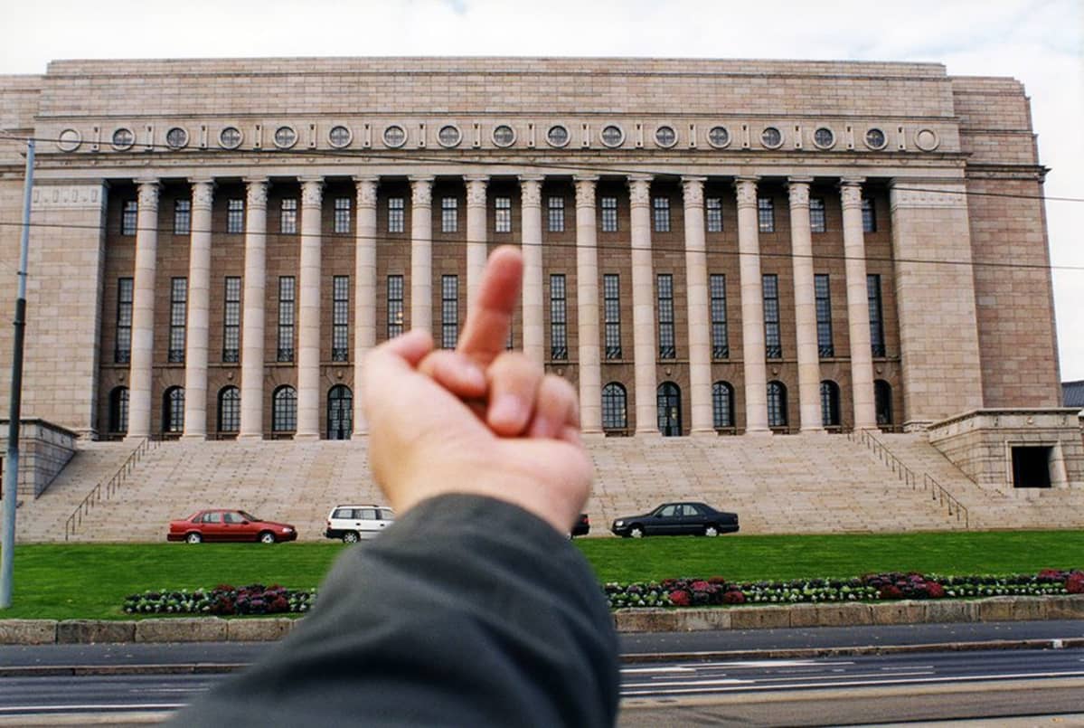 Keskisormea näyttävä käsi eduskuntatalolla.