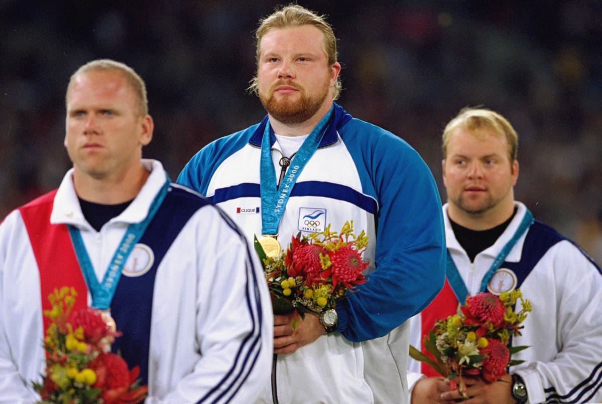 Arsi Harju (kesk.) voitti olympiakultaa Sydneyssä tuloksella 21,29. Hopeaa sai Yhdysvaltain Adam Nelson (taka-alalla), 21,21, ja pronssia hänen maanmiehensä John Godina (edessä), 21,20.