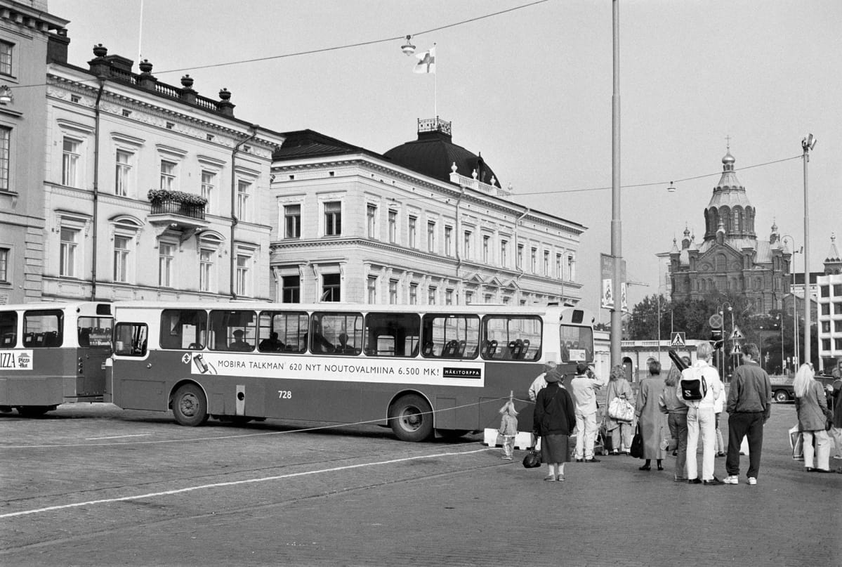 Poliisi sulkee liikenteen busseilla Presidentinlinnan edessä Yhdysvaltain presidentti George Bushin ja Neuvostoliiton presidentti Mihail Gorbatshovin huippukokouksen ajaksi 8.9.1990. Bussin kyljessä mainostetaan matkapuhelinta: "Mobira Talkman 620 nyt noutovalmiina 6.500 mk Mäkitorppa"
