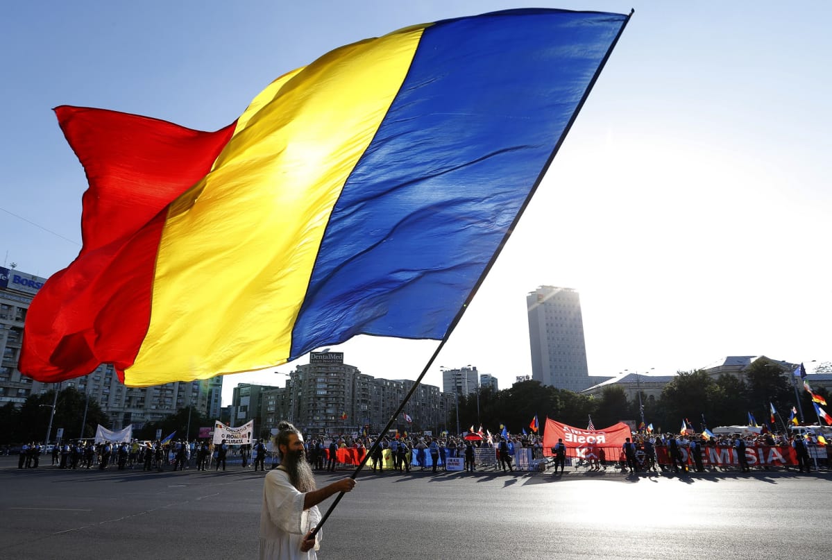 Mielenosoitukset jatkuvat Romaniassa. Ihmiset kantavat Romanian lippuja ja tekstilakanoita.