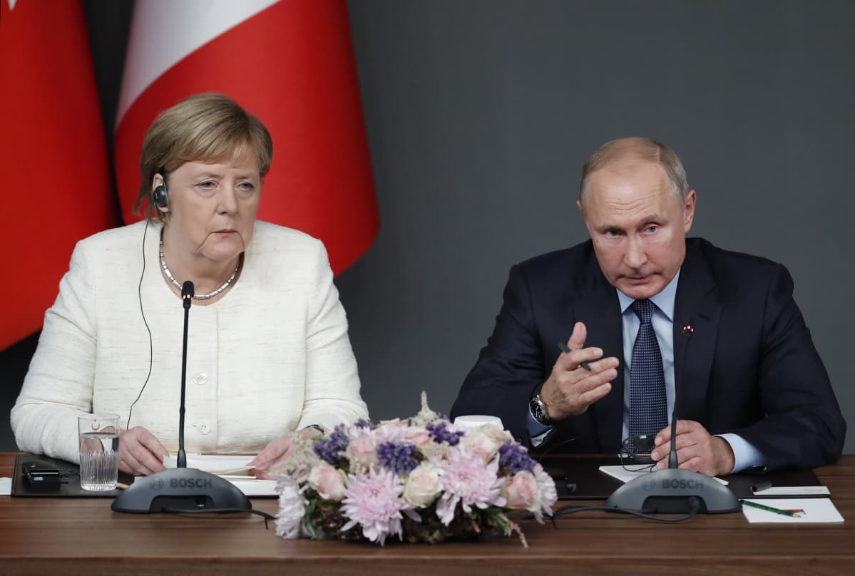 Saksan liittokansleri Angela Merkel ja Venäjän presidentti Vladimir Putin istuvat pöydän ääressä.