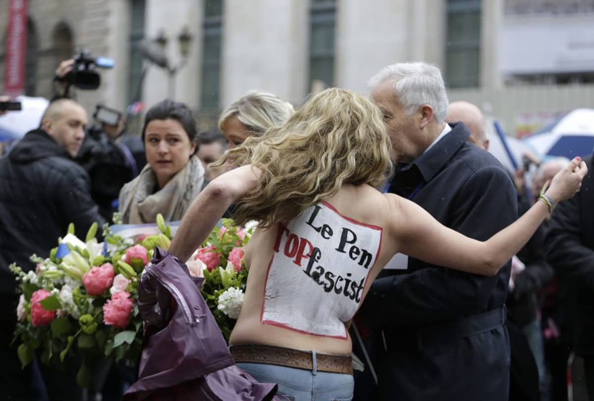 Femen-aktivisti yritti estää Marine Le Penia hänen laskiessaan kukkia Jeanne d'Arcin patsaalle Pariisissa 1. toukokuuta.