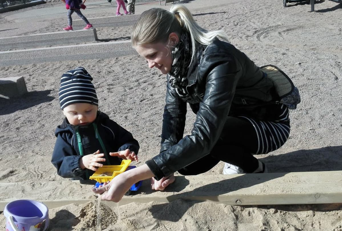 Poika ja äiti leikkivät hiekkalaatikolla