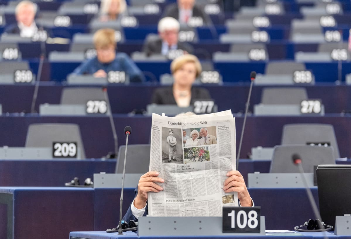 Euroedustaja lukee sanomalehteä istunnon aikana.