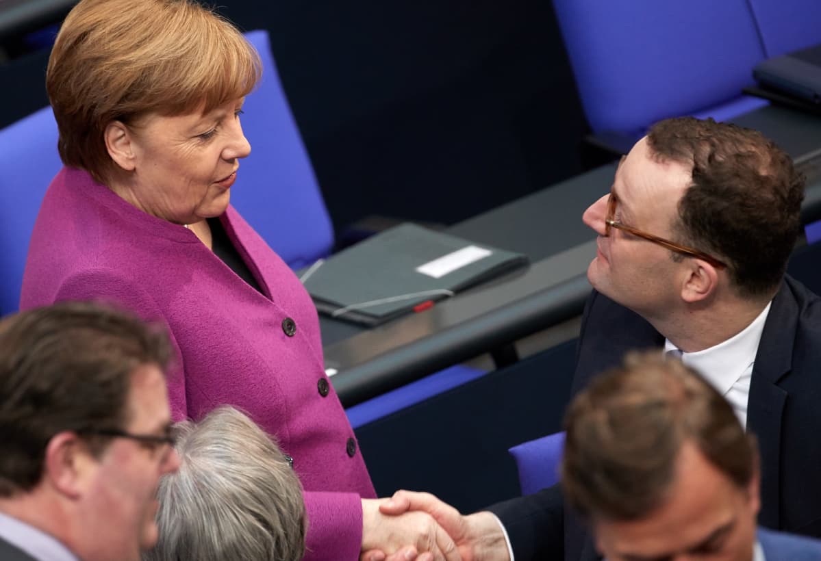 Angela Merkel kättelee Jens Spahnia Saksan parlamentissa 22. helmikuuta.