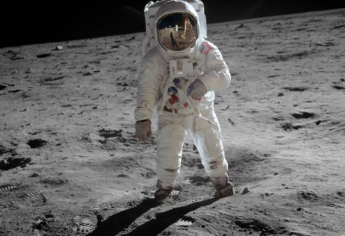 Astronautti kävele Kuun pinnalla. Pölyssä näkyy jalanjälkiä.
