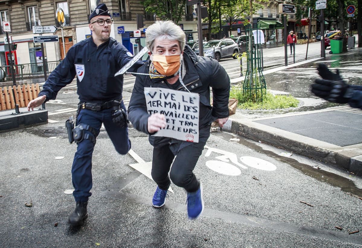 Poliisi yrittää saada mielenosoittajaa kiinni Pariisissa. Vapunpäivän marssit oli peruttu Ranskassa koronaviruksen aiheuttamien liikkumisrajoitusten takia.