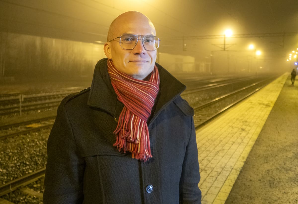 mies seisoo asemalaiturilla sumuisena joulukuun aamuna