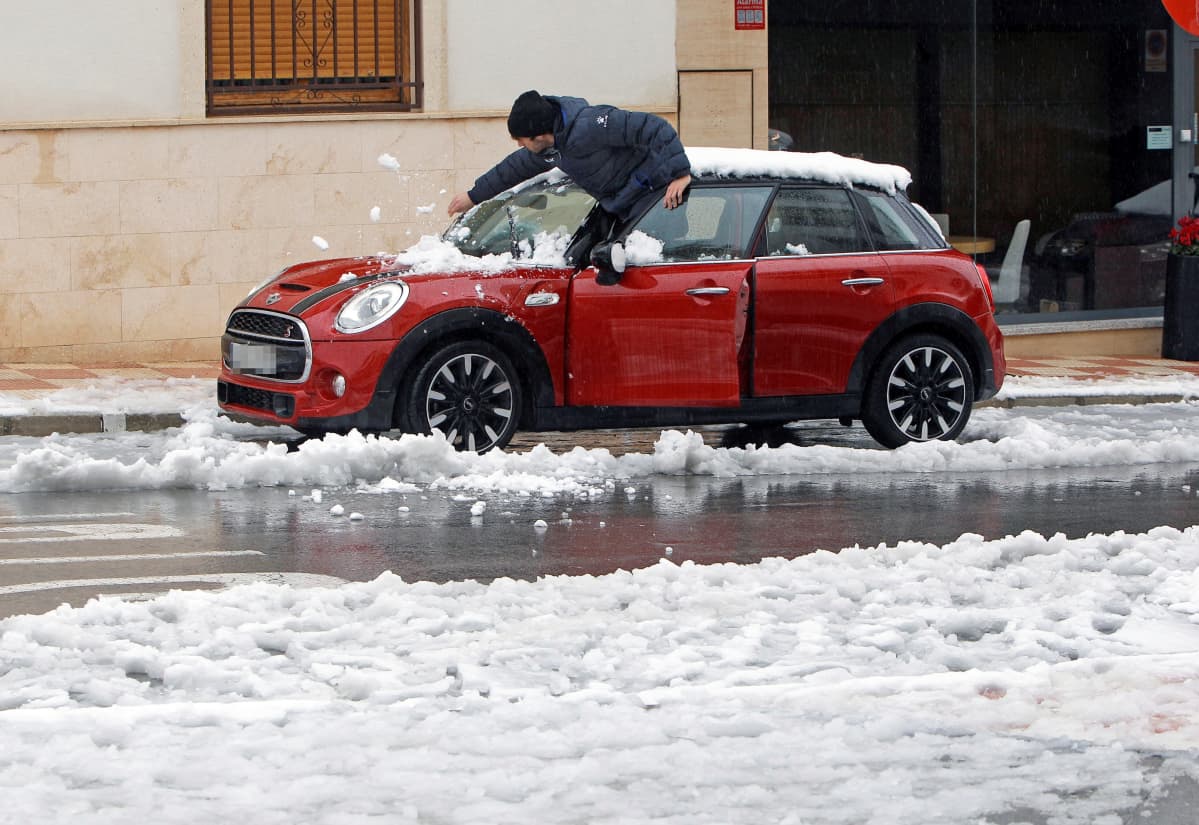 Mies luo lunta autonsa päältä Valenciassa, Espanjassa maanantaina.