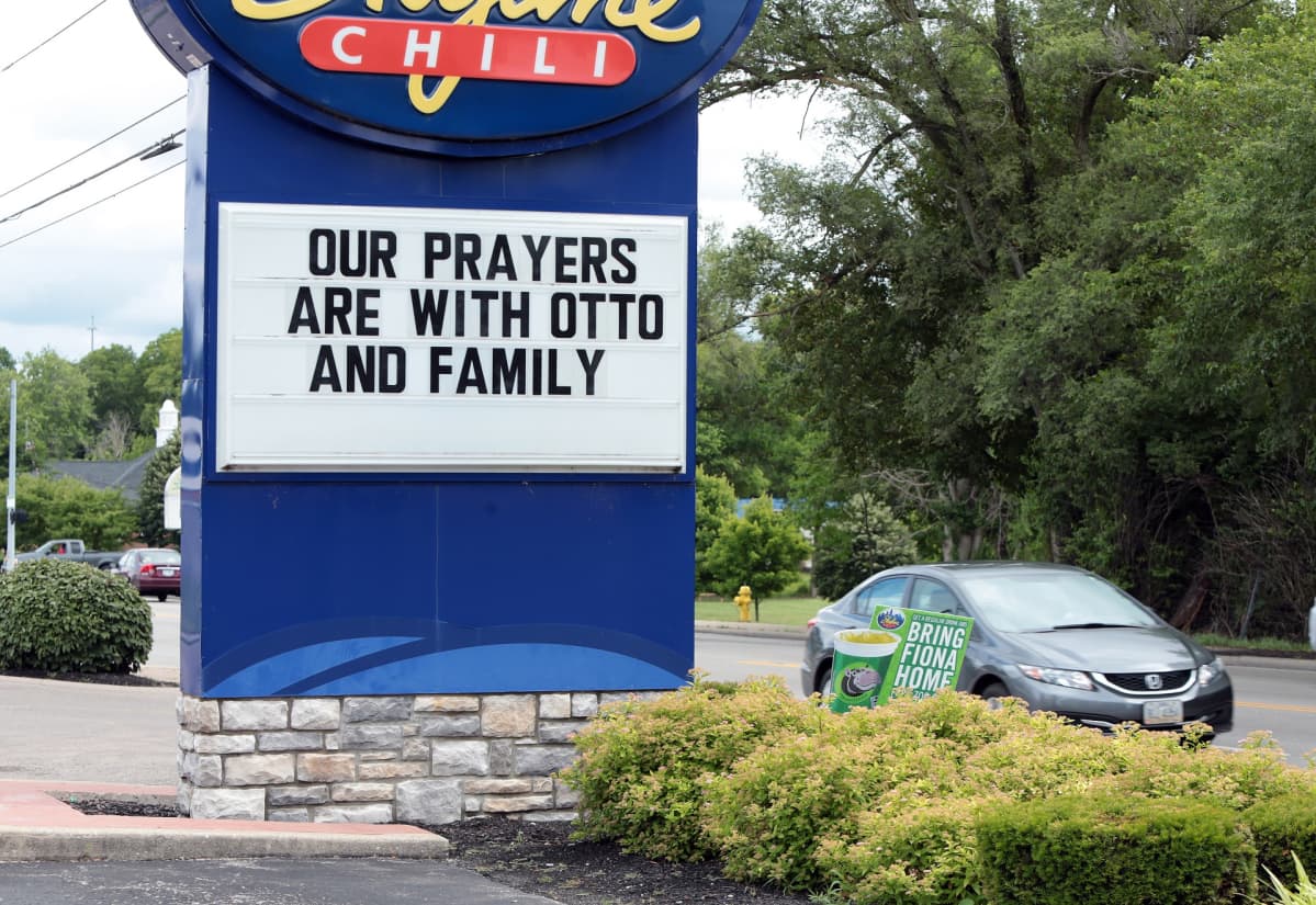 Tien varrella kyltti, jossa teksti Our Prayers are with Otto and Family.