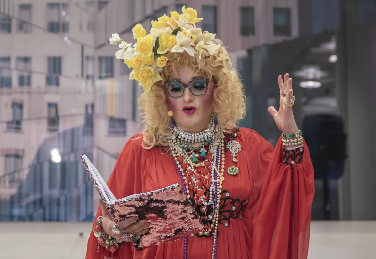 drag-taiteilija Maimu Brushwood o.s. Huolirinta lukee tarinoita yleisölle kirjastossa.