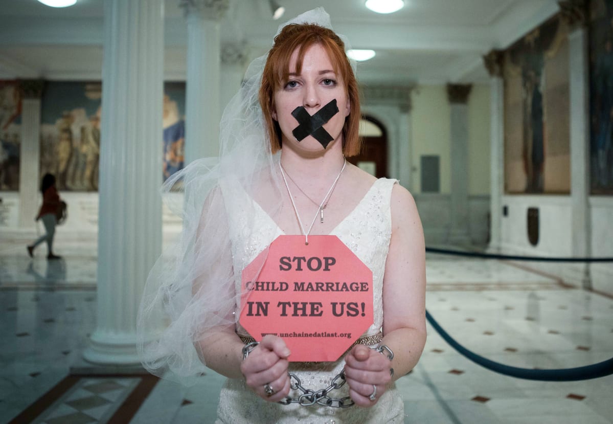 Kuvassa on nainen, jonka kaulassa on kyltti, jossa lukee: Stop child marriage in the US!