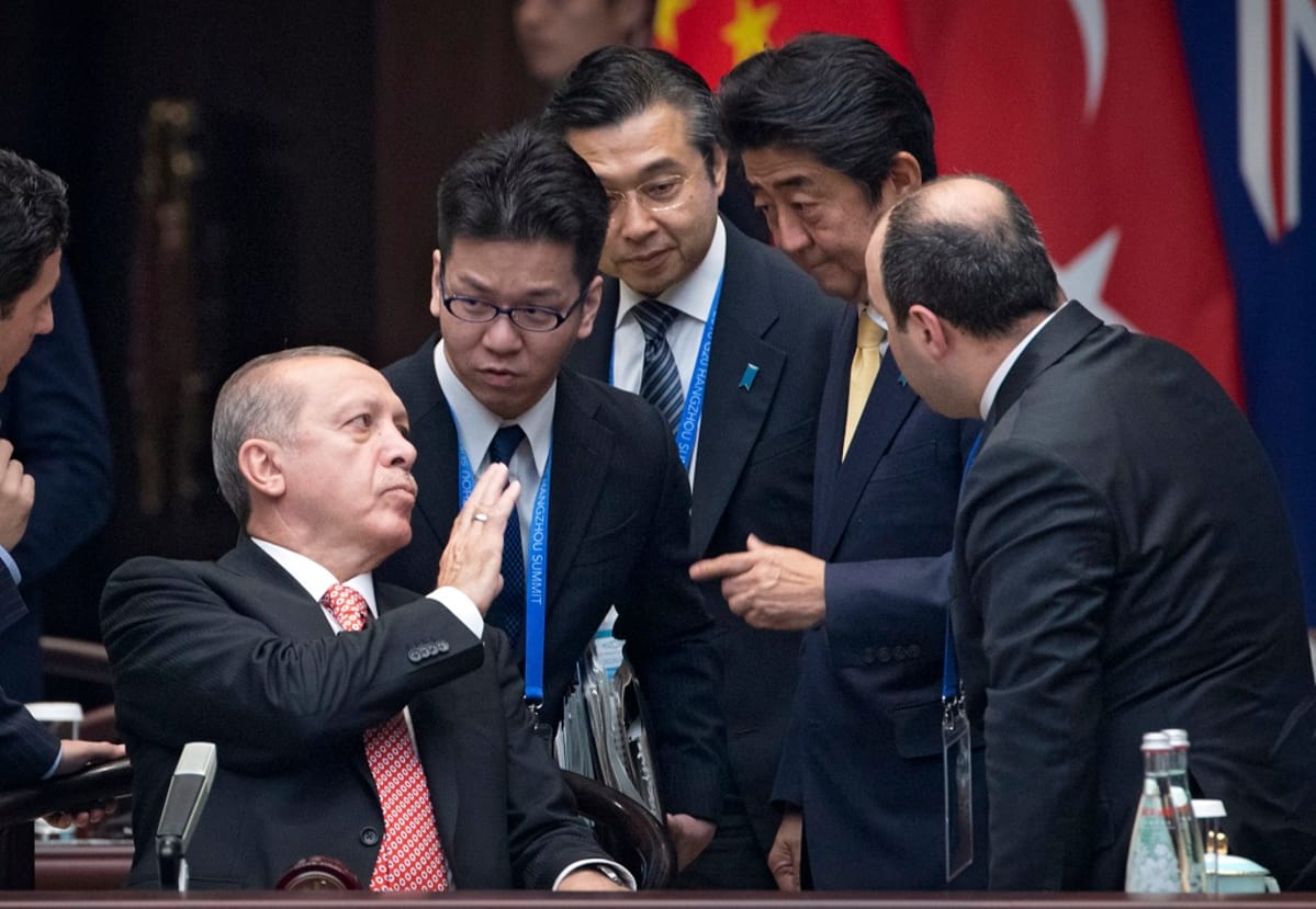 Erdoğan istuu, miehet ympärillä seisovat.