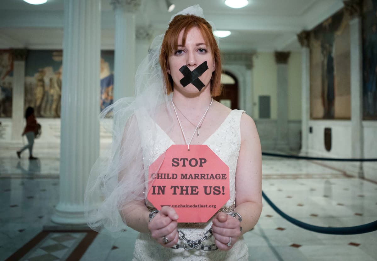 Kuvassa on nainen, jonka kaulassa on kyltti, jossa lukee: Stop child marriage in the US!