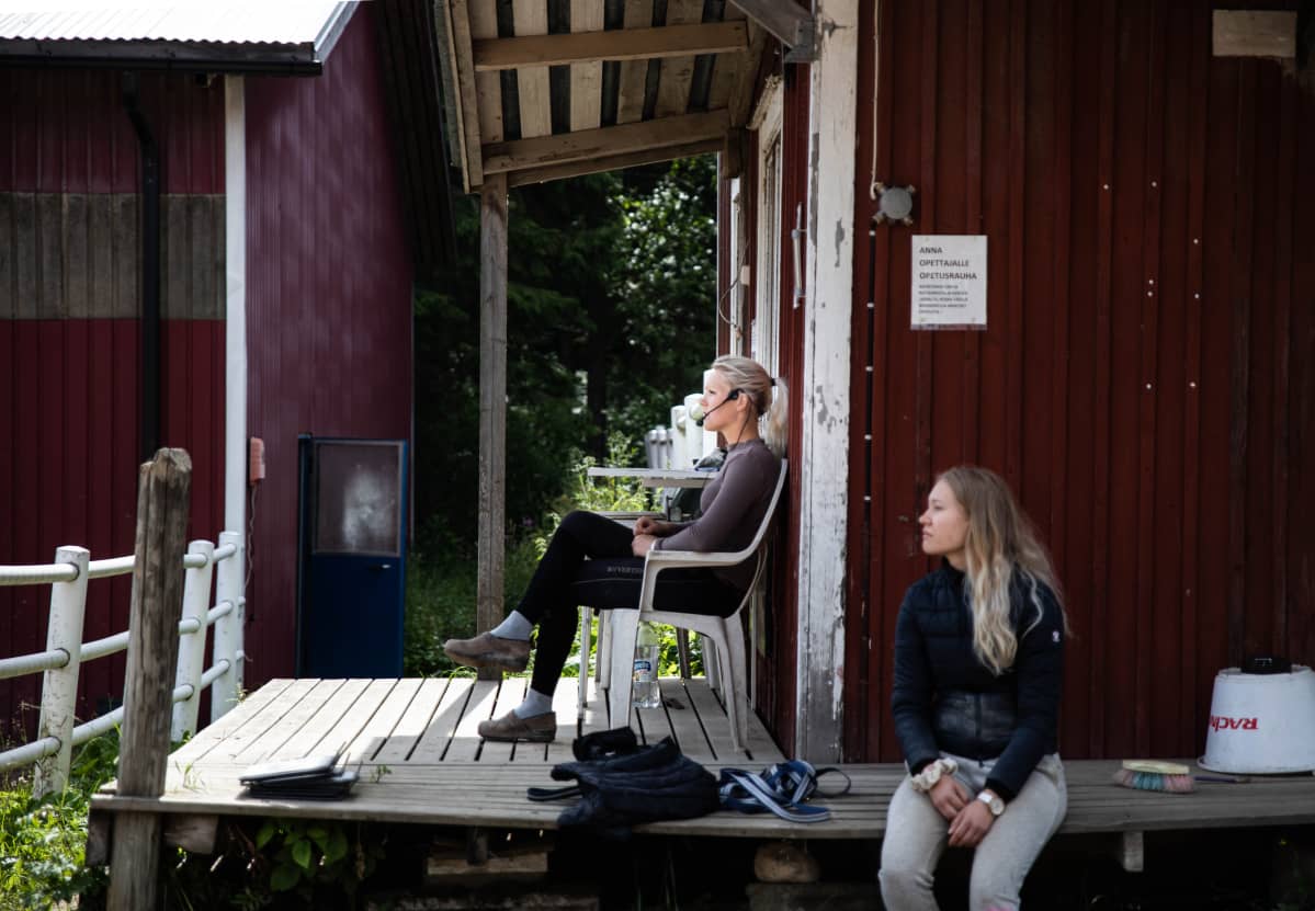 Ratsastuksen opettaja istuu kentän ulkopuolella ja ohjaa tuntia.