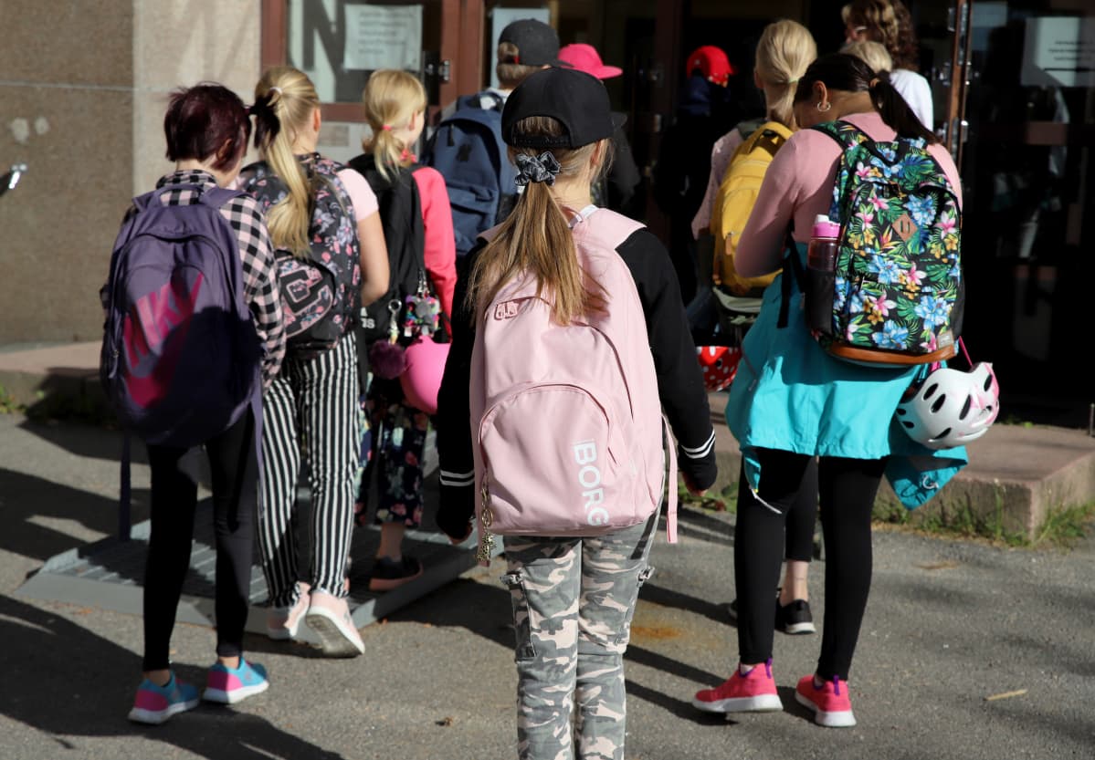 oppilaat kävelevät jonossa sisään koulurakennukseen