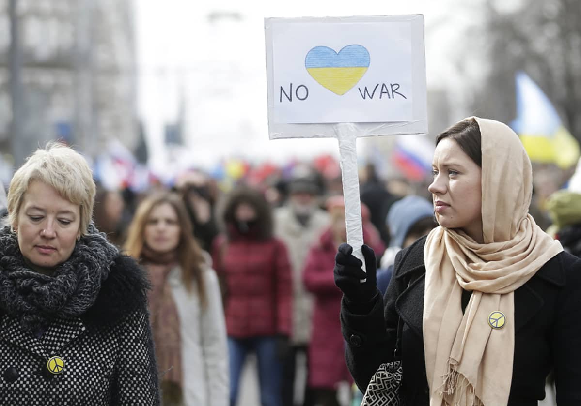 Nainen pitelee No war -kylttiä.