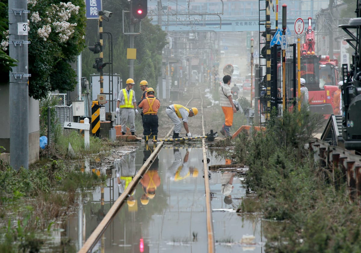 Rankkasateet katkaisivat useita junayhteyksiä läntisessä Japanisa. Raidetyöntekijät korjaavat tulvan vaurioittamaa rataa Hiroshimassa.