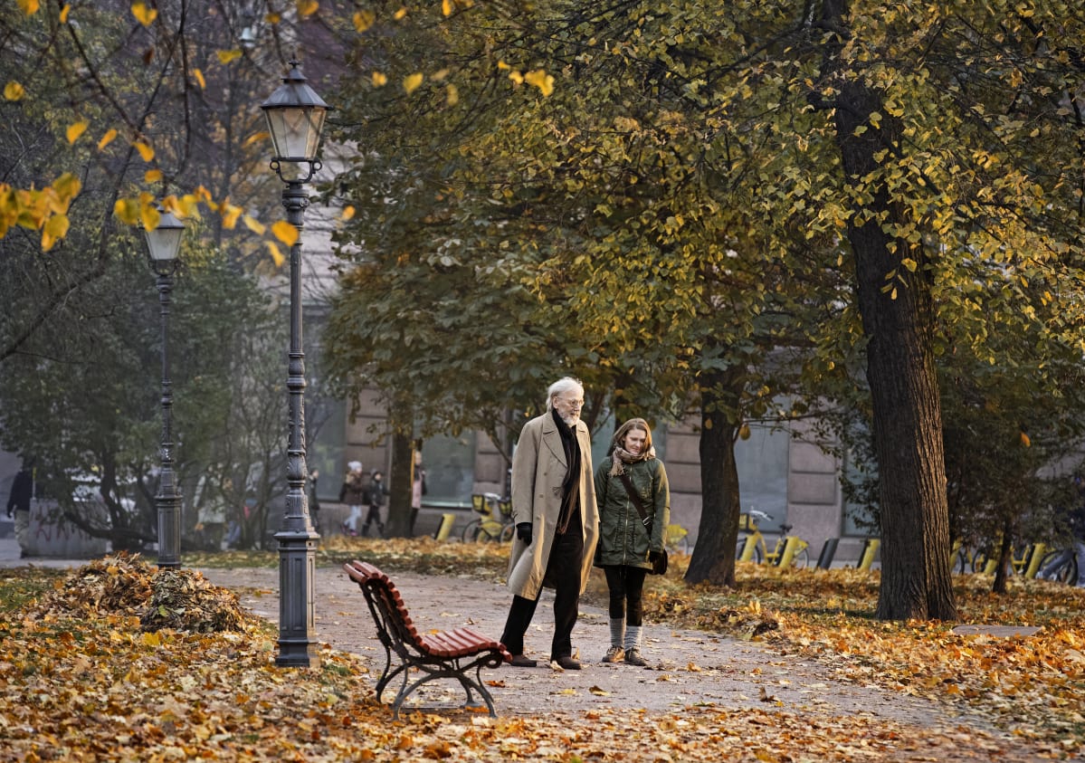 Olavi (Heikki Nousiainen) och Lea (Pirjo Lonka) promenerar tillsammans i en höstlig park.