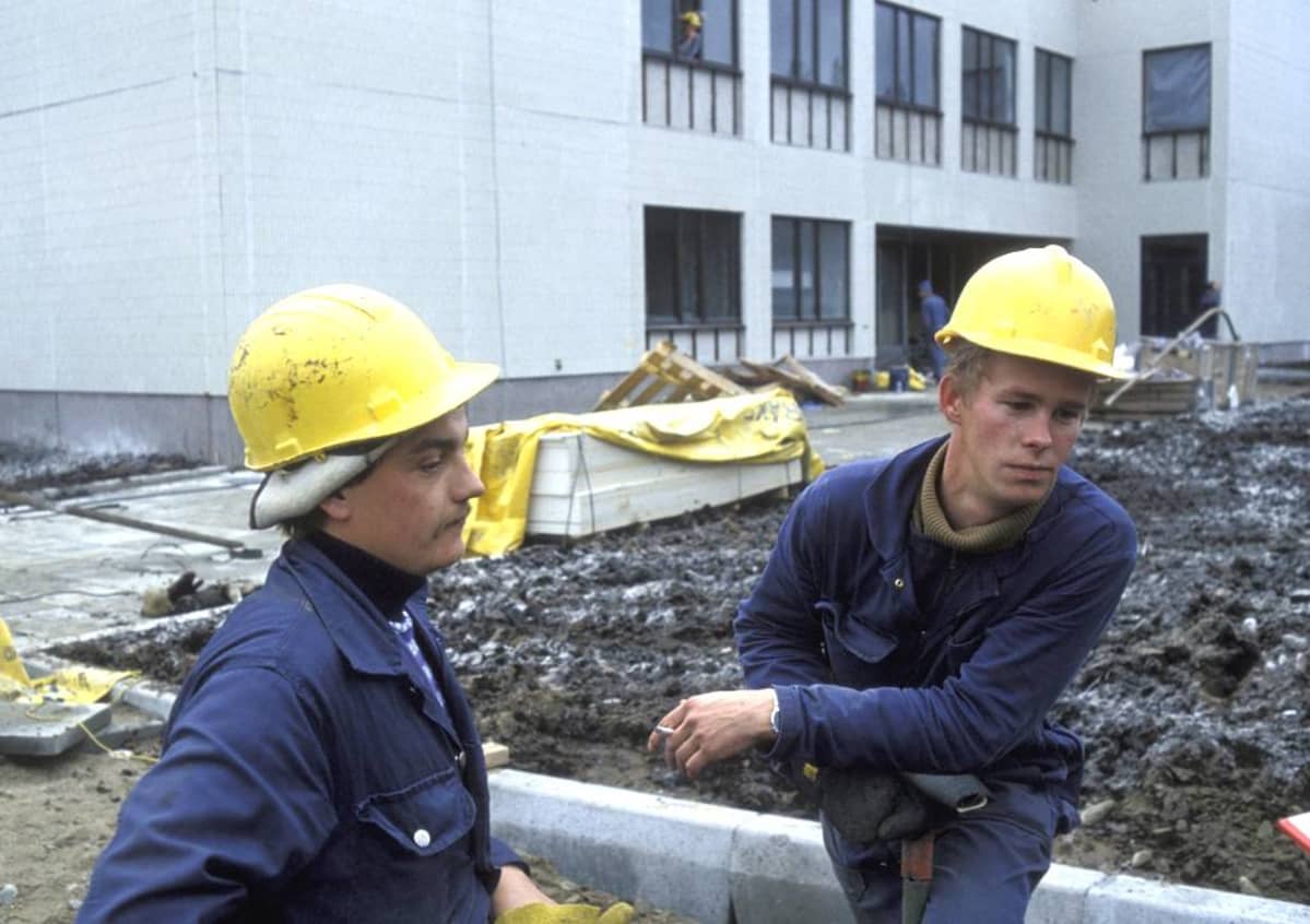 Kuva otettu Kostamuksessa 14.10.1981, kahdella suomalaisella rakennusmiehellä on siniset haalarit ja keltaiset turvakypärät.