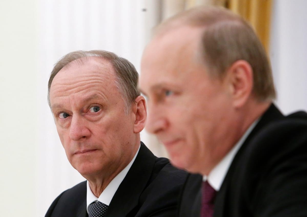 Nikolai Patrushev katsoo Putinia, joka on kuvan etualalla. Kuva on tarkennettu Patrushevin kasvoihin, Putin on kuvassa häimeä.