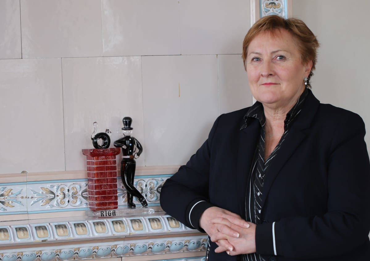 Aino-Maija Luukkonen nojaa kakluuniin.