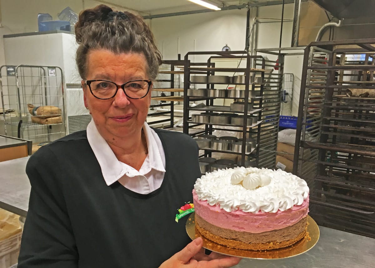 Leipomoyrittäjä Sirpa Santala seisoo täytekakku kädessä Leipomo Sorttiinan tuotantotiloissa.